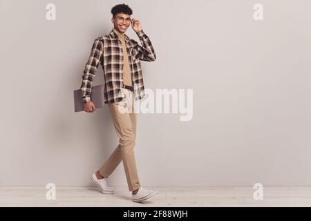 Full length body size photo of guy keeping laptop stepping on meeting smiling isolated grey color background Stock Photo