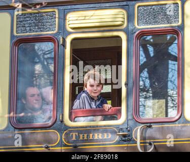 Bewdley, UK. 12th April, 2021. It's full steam ahead on the Severn Valley Railway as this ever-popular heritage railway reopens following the easing of lockdown restrictions today. The family captured here on board the passing 'Adventurer' service are returning home to Bridgnorth after a fabulous day riding the rails. Credit: Lee Hudson/Alamy Live News Stock Photo