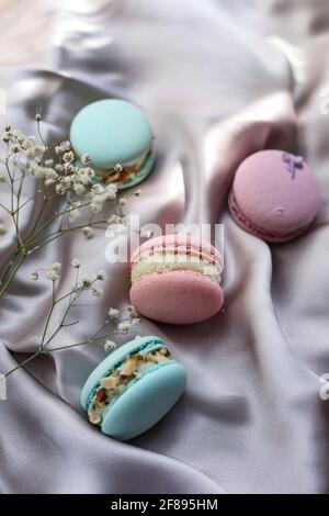 pink and mint french macaroons or macarons cookies and a white flowers on a cloth background. Natural fruit and berry flavors, creamy stuffing for Stock Photo