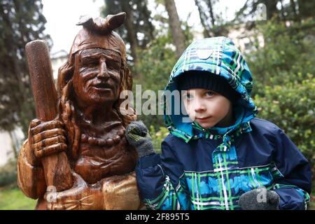 Child with wooden sculpture of Baba Yaga in Gurzuf Park in spring Stock Photo