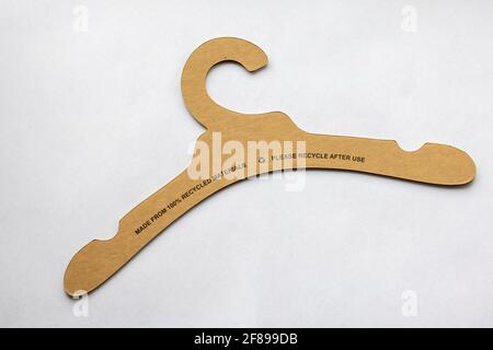 A portrait of a recyclable clothes hanger made of cardboard and paper lying on a white background with the recycle instructions on it. This is an envi Stock Photo