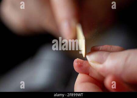 A close up portrait of a mother filing the nails of a small baby hand after clipping them. The childs fingernails are being filed with a small file be Stock Photo