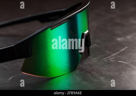 Sports glasses with a green mirrored lens on a black textured background. Free space. Stock Photo