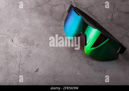 Sports glasses with a green mirrored lens on a black textured background. Free space. Stock Photo