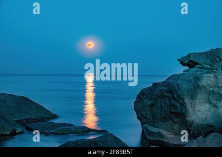 Super full blood moon and moon light over the sea. Full red moon with reflection in water with details of the lunar surface. Stock Photo