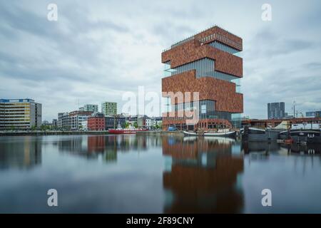 Antwerp, Belgium - 04.29.2018: Low angle, long exposure shot of modern building of MAS museum on a cloudy, rainy day. Reflection in water. Famous arch Stock Photo