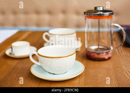 empty leftover tea cups and teapot on wooden table in cafe Stock Photo