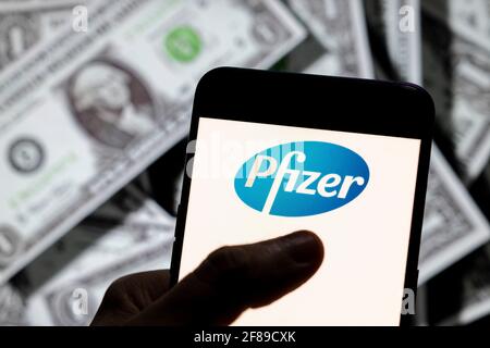 In this photo illustration, the American multinational pharmaceutical corporation Pfizer logo seen on an Android mobile device screen wit the currency of the United States dollar icon, $ icon symbol in the background. Stock Photo