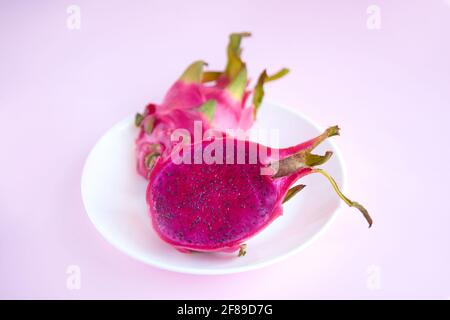 plate with tropical Dragon fruit pitaya. nutrition ripe raw asian fruits delicious. pitahaya cut into 2 halves on pink background Stock Photo