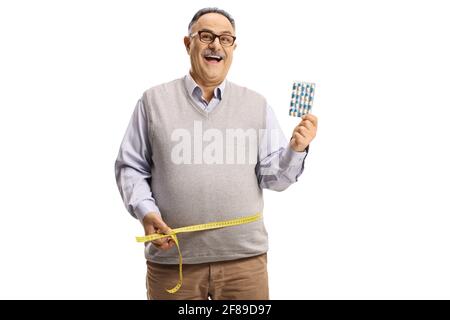 Happy mature man holding slimming pills and measuring his waist isolated on white background Stock Photo