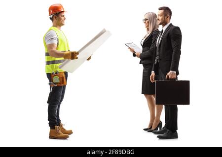 Full length profile shot of a construction worker holding a blueprint and talking to a businesswoman and businessman isolated on white background Stock Photo
