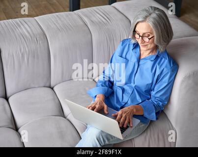 Top angle shot on couch at home of older female advanced user of ecommerce. Stock Photo