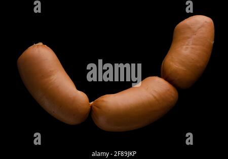Three boiled sirloin sausages, on a black background isolated Stock Photo