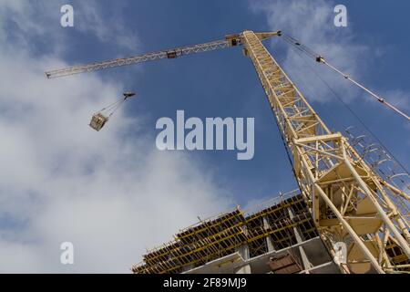 Tower crane on the background of the facade of the building. Lifting mechanism on the construction site Stock Photo