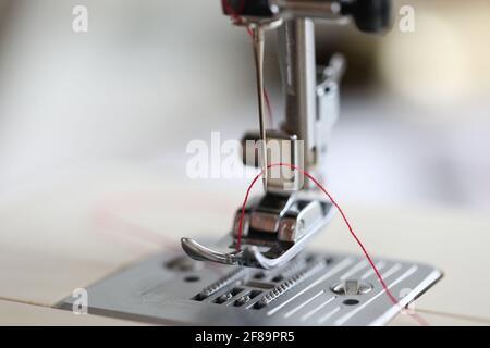 Close-up of red thread in sewing machine. Macro shot of metal details of equipment Stock Photo
