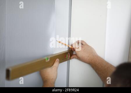 Close-up of professional worker using level for wall and pencil Stock Photo