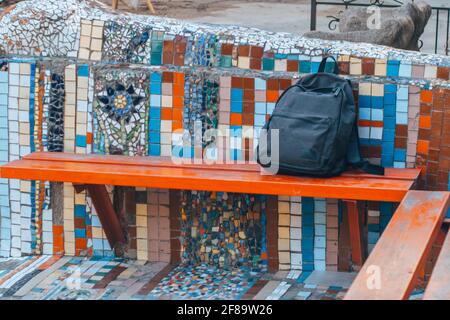 A lost backpack lying on a park bench. Stock Photo