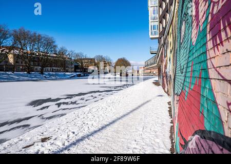 graffiti wall at small Weser at Bremen Teerhof completely frozen and covered in snow at the sun in winter Stock Photo