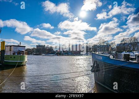 shot through two ships on the weser river - the ms treue and ms rügen - with werdersee island in the background in the sun at winter days in bremen Stock Photo