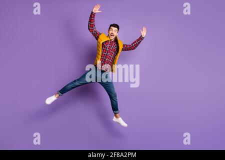 Full size photo of optimistic guy jump wear shirt jeans vest isolated on violet color background Stock Photo