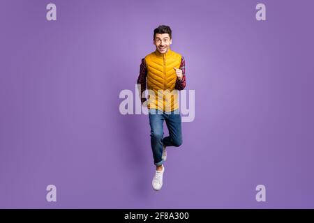 Full size photo of optimistic funky guy run wear shirt jeans vest isolated on violet background Stock Photo
