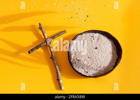 Good Friday, Ash Wednesday, Lent Season and Holy Week concept. Christian cross and ashes on yellow background. Flat lay. Copy space. Stock Photo