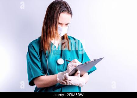 Beautiful pretty young woman doctor surgeon with mask and stethoscope showing a blood pressure monitor in front concept heart care heart disease heart Stock Photo