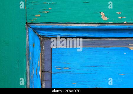 Close-up Abstract Background of Colorful Wooden Door with Peeling Paint in Green, Blue and Purple Stock Photo