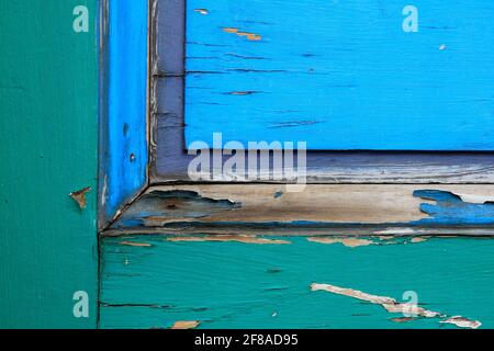 Close-up Abstract Background of Colorful Wooden Door with Peeling Paint in Green, Blue and Purple Stock Photo