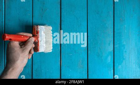 Hand-painted brush on a wooden wall, countertop, blue. Brush in hand,  painting work Stock Photo