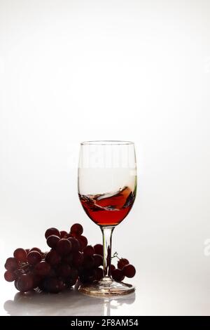 Red wine in glass with red grape. Stock Photo