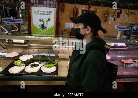 Moscow, Russia. 11th of April, 2021. Customer wearing protectuve face mask shops at the Yeliseyevsky store (the meet department of the store) at Tverskaya Street on last day before closing to the store reconstruction. The store was opened by merchant Grigory Yeliseyev in 1901 as Eliseev's Shop and Cellars of Russian and foreign wines. The store marked the 120th anniversary since its opening on February 5, 2021 Stock Photo
