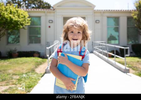 Child with rucksacks standing in the park near school. Pupils with books and backpacks outdoors. Kid with backpack going to school. Kids education Stock Photo