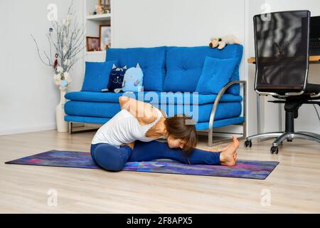 Full length portrait of young woman doing yoga pose dedicated to the sage marichi I Stock Photo