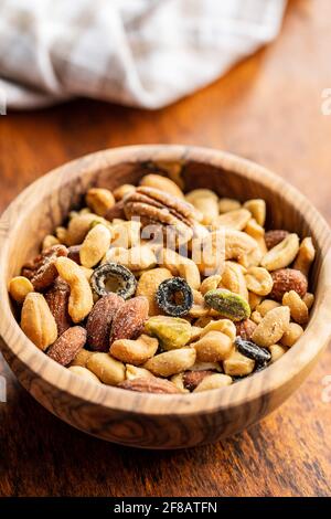Mix of salted nuts in bowl on wooden table. Stock Photo