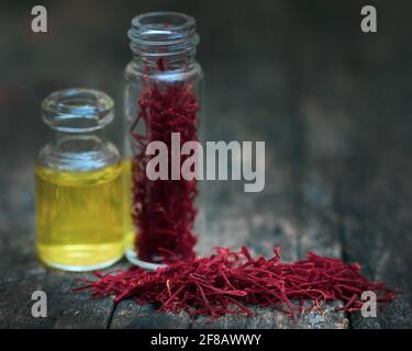 Closeup of Saffron with extract in a bottle on natural surface Stock Photo