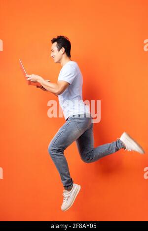 Asian businessman jumping and holding laptop Stock Photo