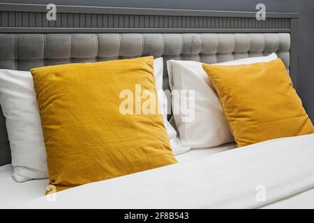 Bed with gray color velvet headboard and bright yellow pillows. Stock Photo