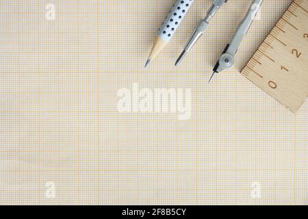 Wooden ruler, compasses and pencil lie on graph paper Stock Photo
