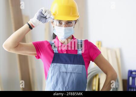 Woman builder in yellow hard hat and protective mask