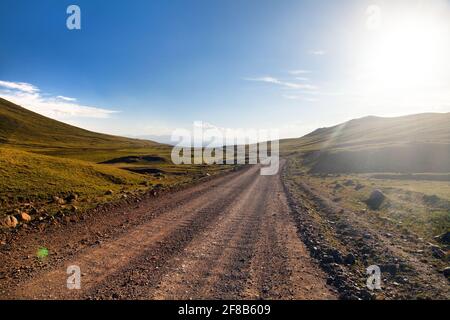 Unpaved road and yurts near Son-Kul lake and Tian Shan mountains in Kyrgyzstan Stock Photo