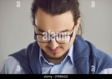 Closeup portrait of smart young man in glasses and shirt on gray studio background Stock Photo