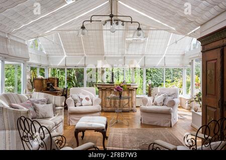 Pair of armchairs and sofa in conservatory extension of 1930s West Sussex coastal home Stock Photo