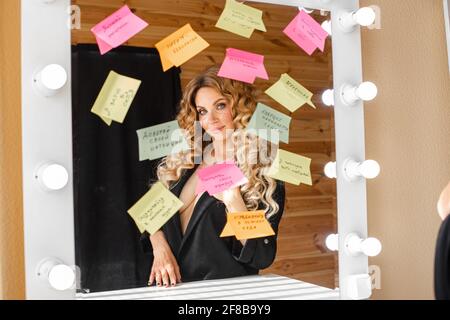 Belarus Minsk 23 09 2020: Smiling lady looking at her reflection in the studio mirror Stock Photo