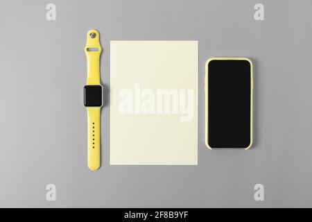 Yellow mobile phone and watch on clean gray office desk Stock Photo