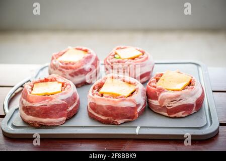 Making home made Beer Can Bacon Burgers on barbecue grill. Preparing stuffed patties, wrapped  in bacon. Stock Photo