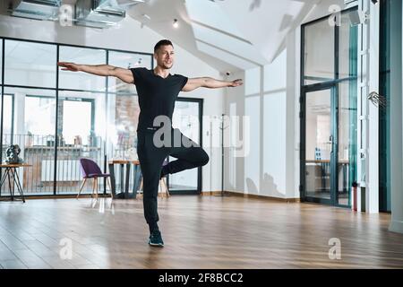 Sportive man standing in yoga pose with spread arms Stock Photo