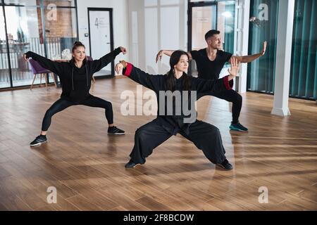 Three people doing high pat on horse single whip stance Stock Photo
