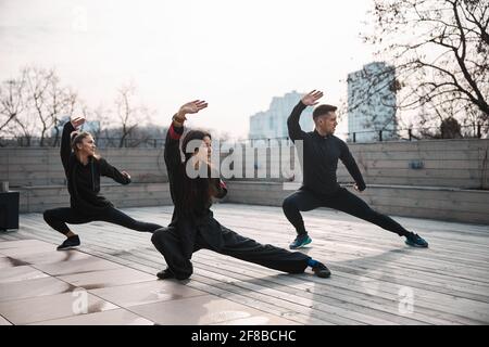 Three people doing tai chi deep side lunge Stock Photo
