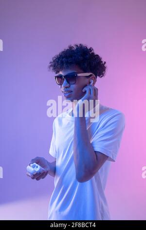 Young mulatto guy in headphones and in sunglasses looking stylish Stock Photo